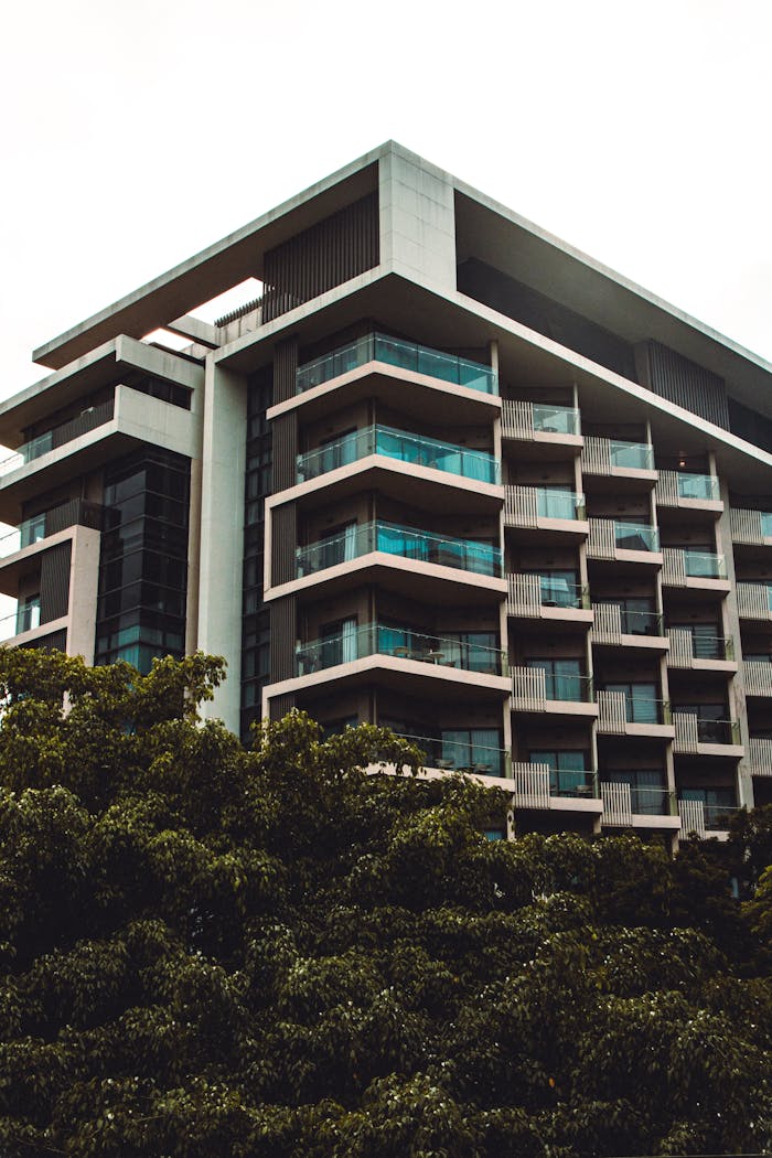 Services Low angle view of a modern residential building with balconies amidst greenery.